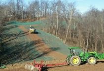 Green tractor plowing field for erosion control